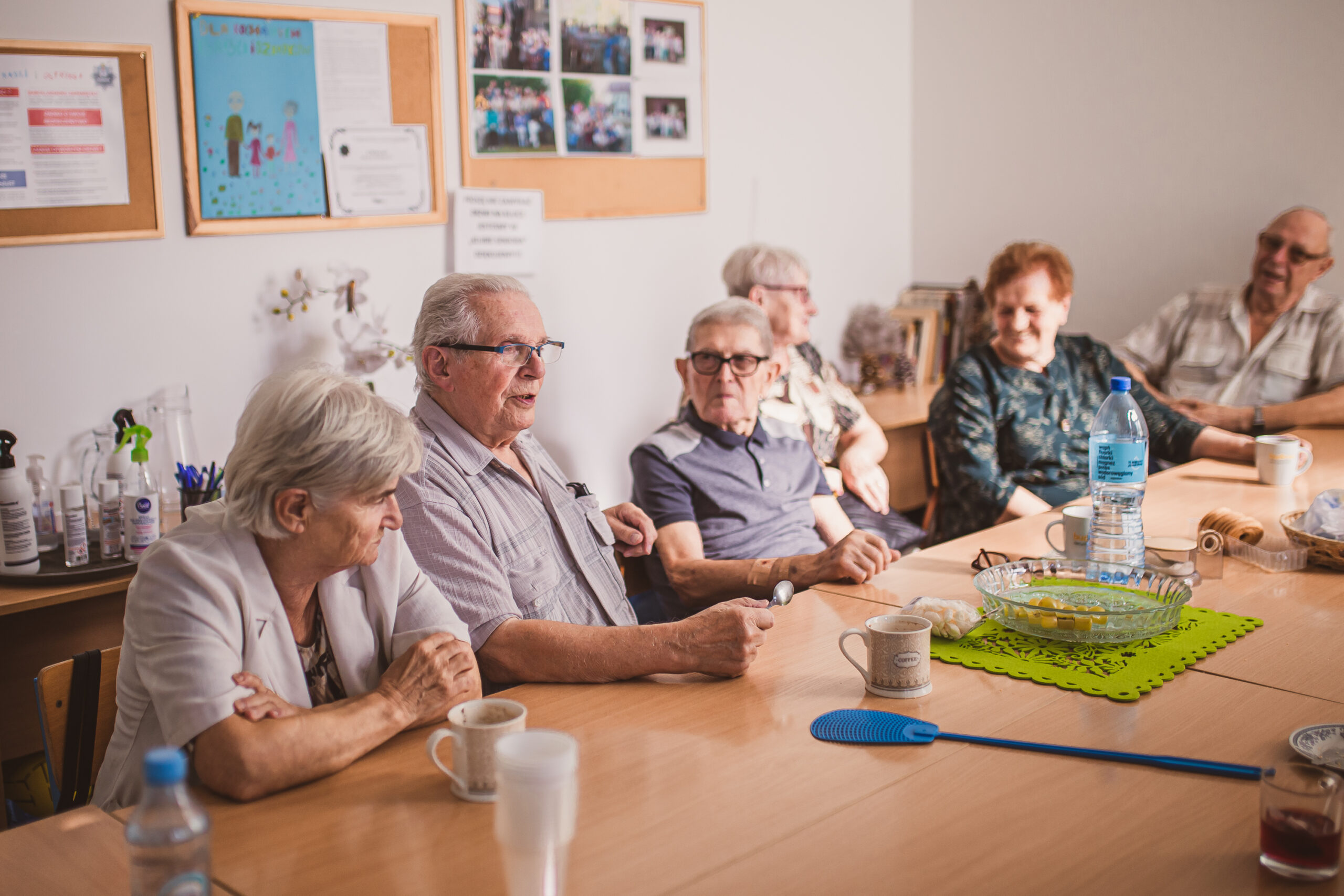 zdjęcie przedstawia grupę sześciorga seniorów siedzących przy stole i rozmawiających podczas warsztatów poste restante